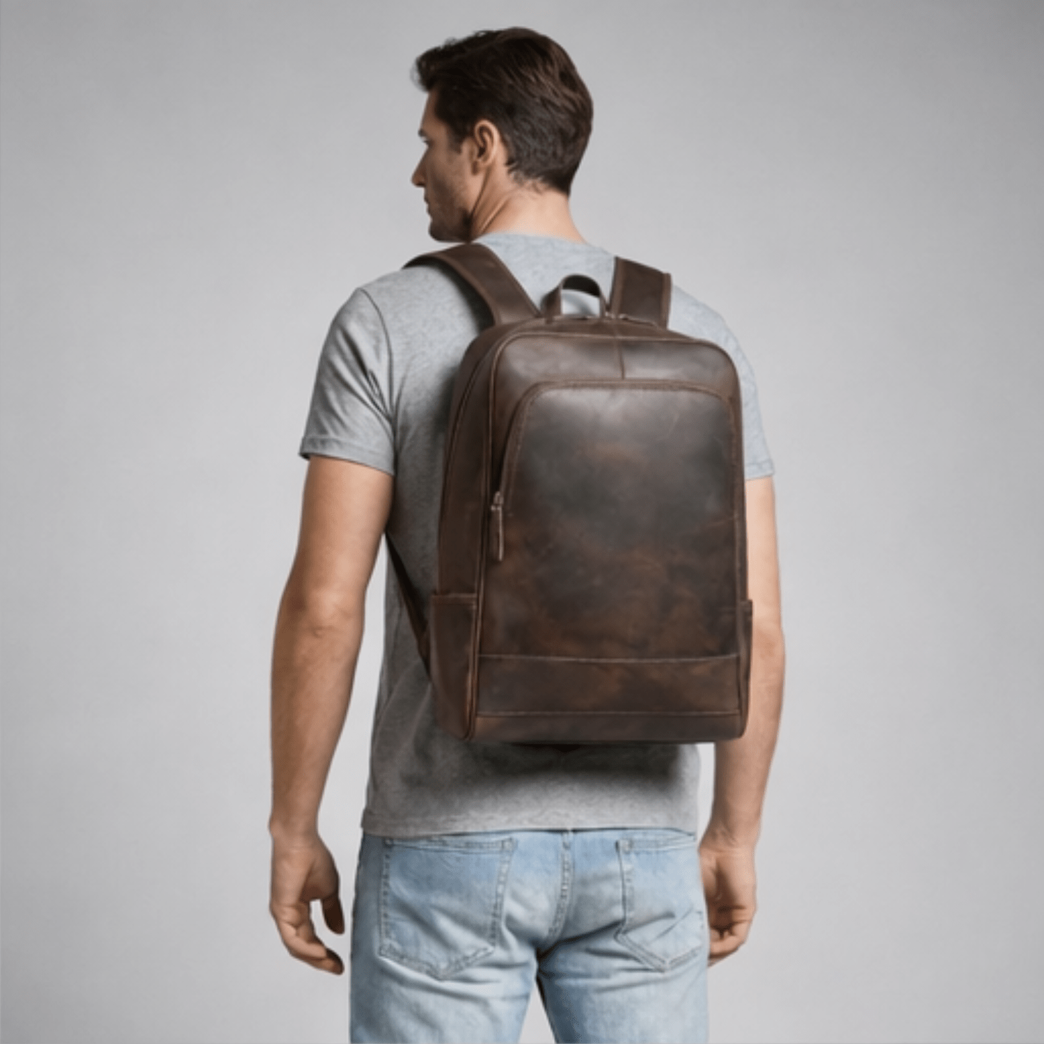 Man wearing a brown leather backpack on a gray background
