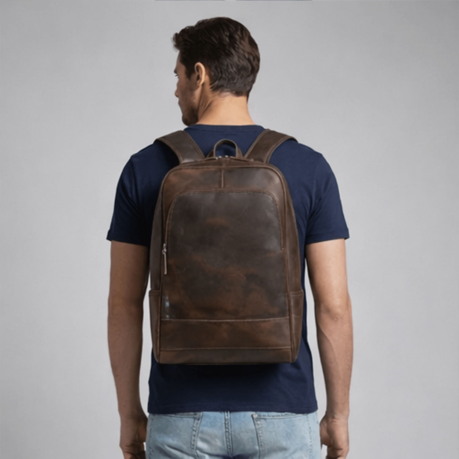 Man wearing a brown leather backpack on a gray background