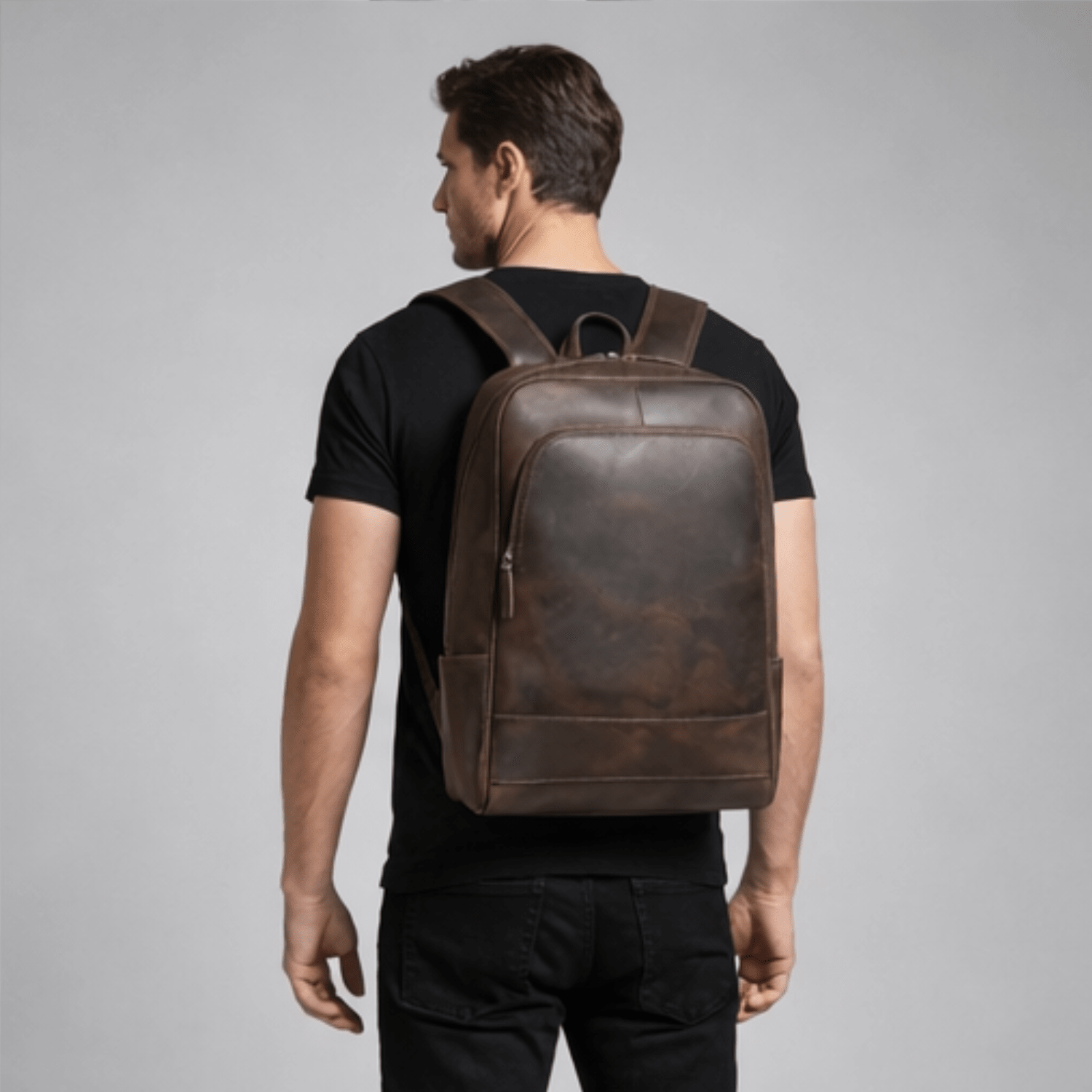 Man wearing a brown leather backpack against a gray background