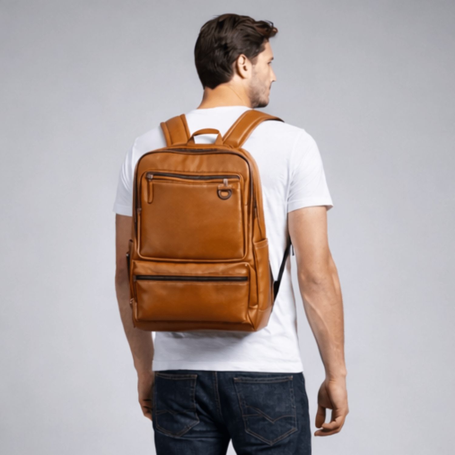 Man wearing a brown leather backpack on a gray background