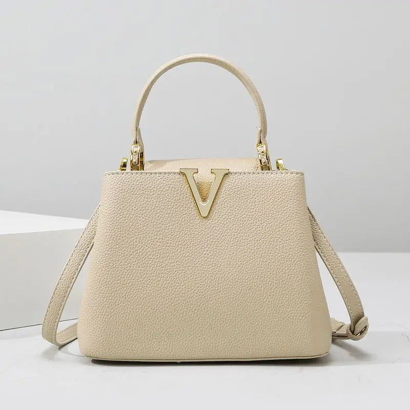 Beige handbag with a gold logo on a light gray background