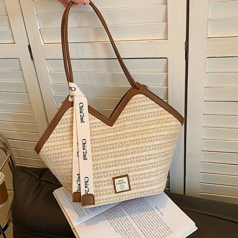 Beige tote bag with brown handles and strap on a surface with a blurred background