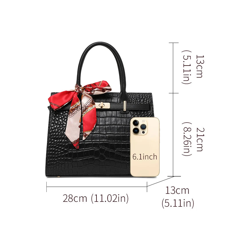Black handbag with a red scarf and phone for scale on a white background