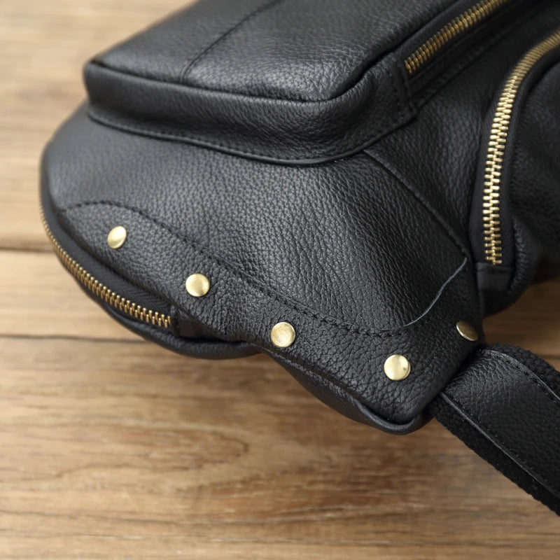 Black leather bag with gold zippers and studs on a wooden surface