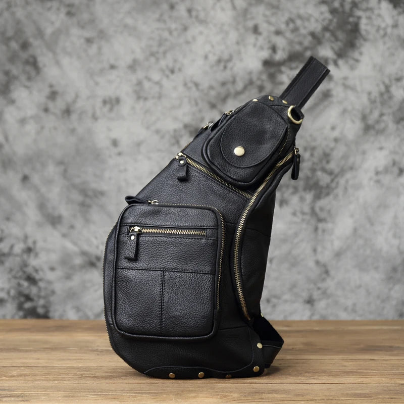 Black leather sling bag on a wooden surface with a gray textured background