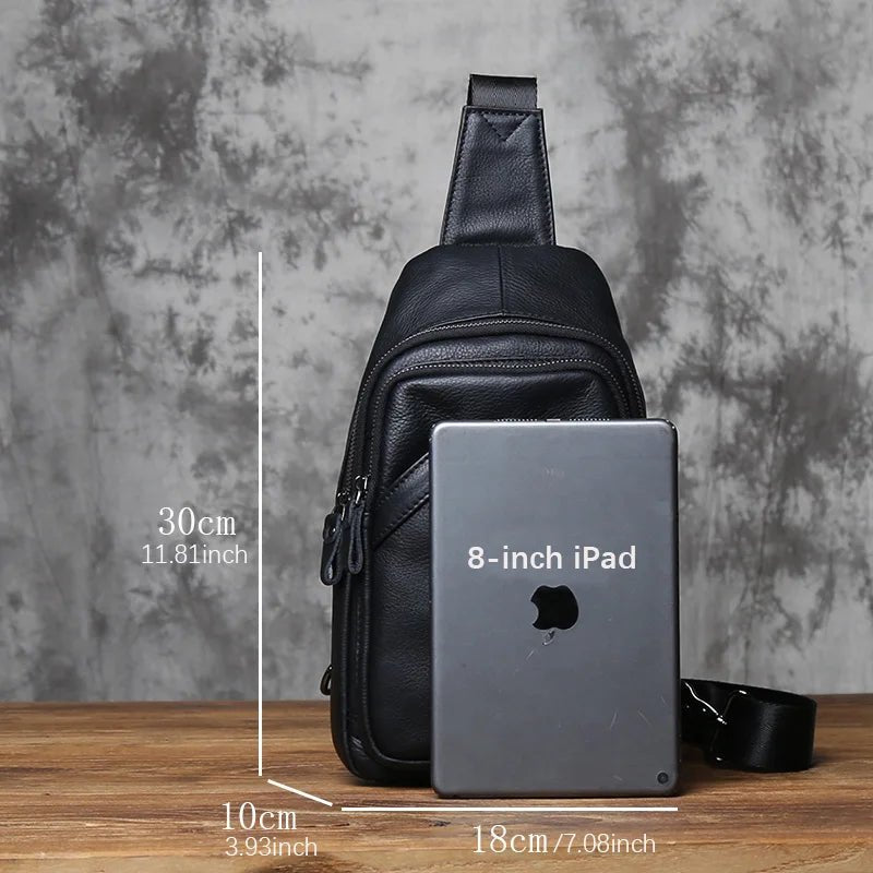 Black leather sling bag with an 8-inch iPad for size comparison on a wooden surface.