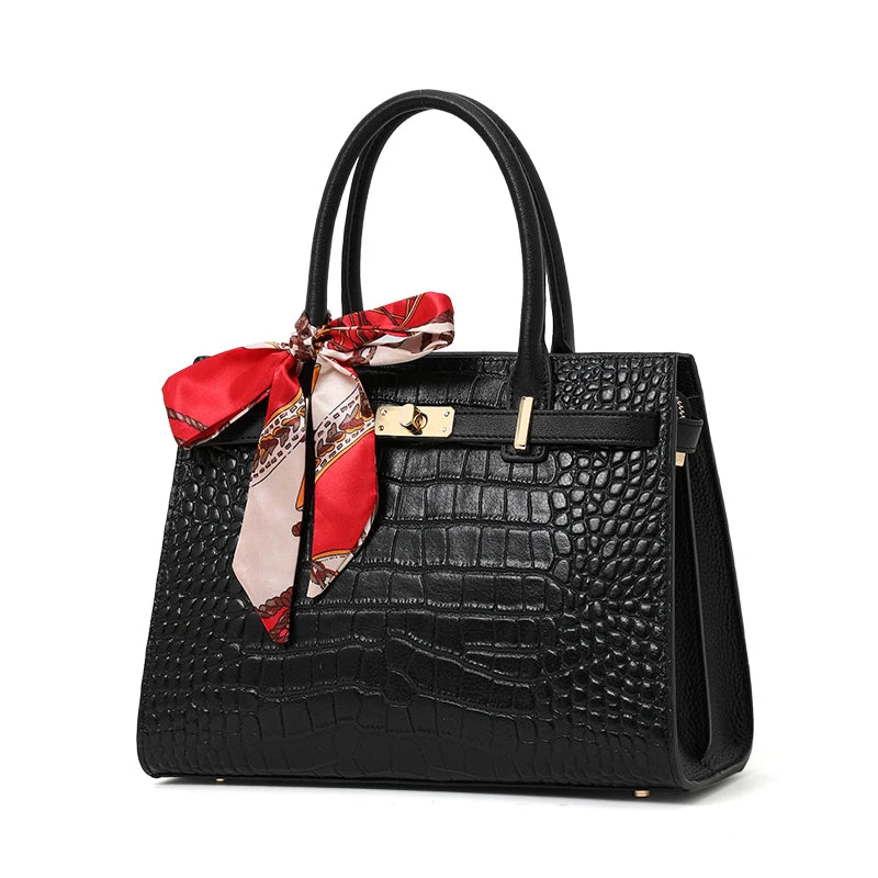 Black textured handbag with a red and beige scarf on a white background