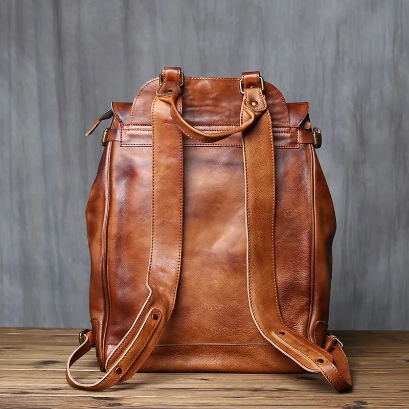 Brown leather backpack on a wooden surface with a gray background