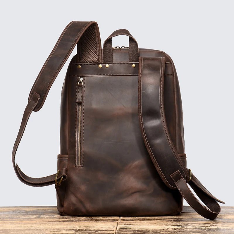 Brown leather backpack on a wooden surface with a light gray background