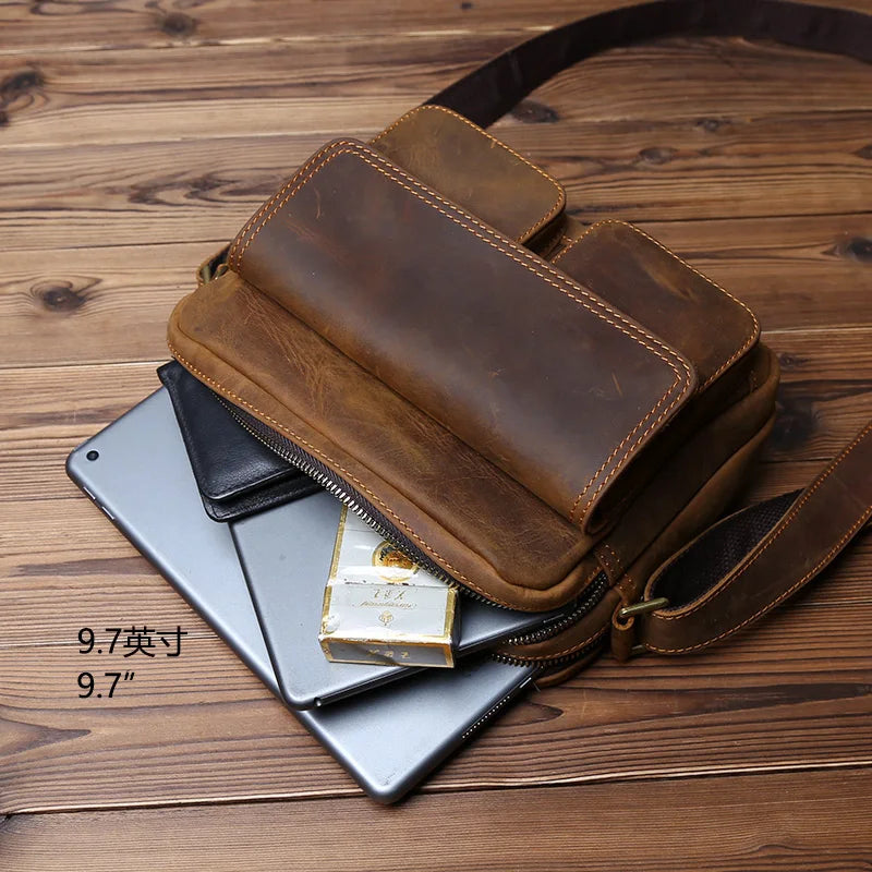 Brown leather crossbody bag with a phone and wallet on a wooden surface