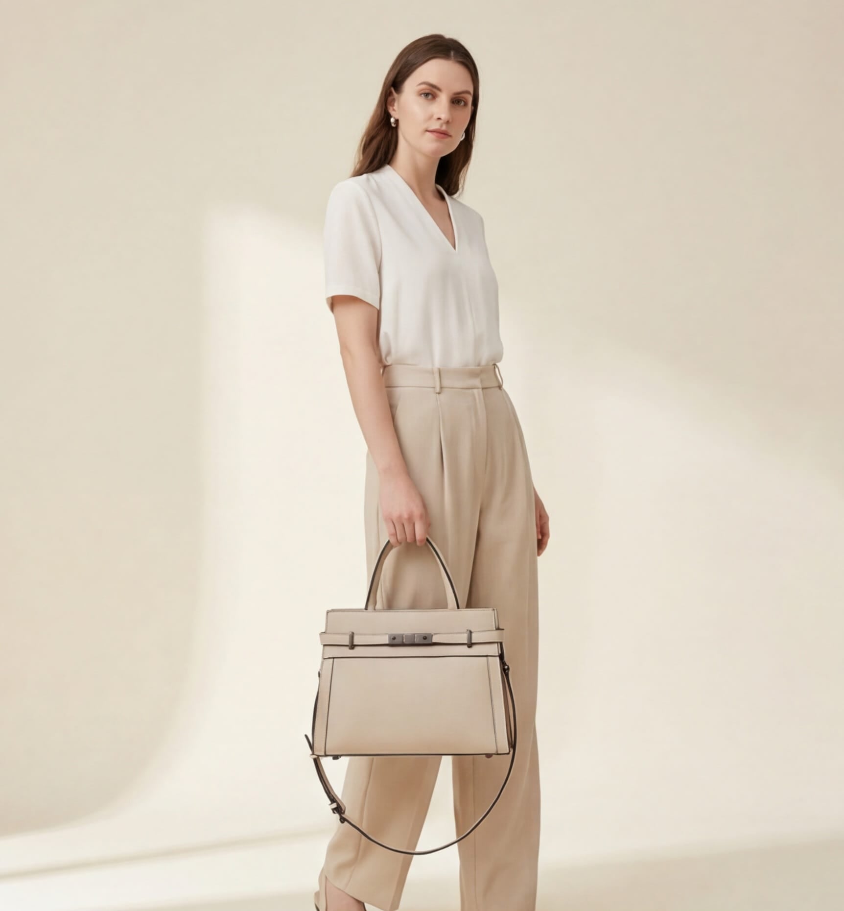 Woman holding a beige handbag against a plain background