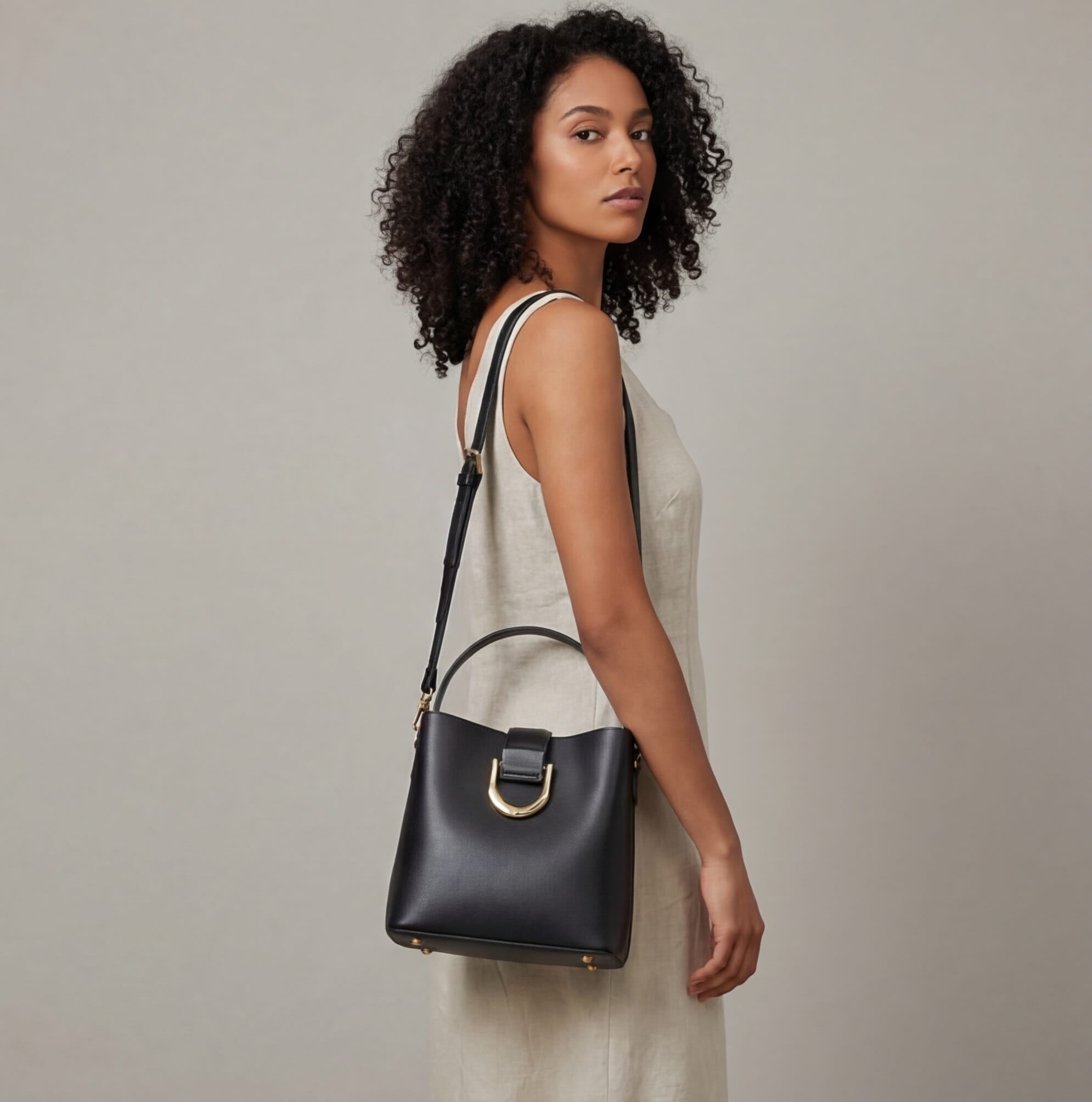 Woman holding a black handbag against a neutral background
