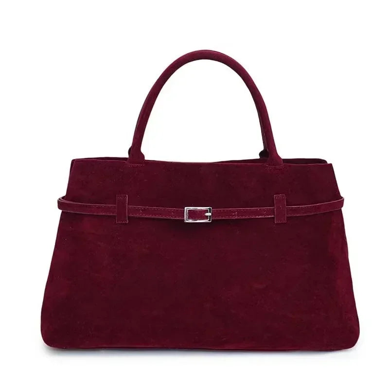 Maroon handbag with a silver buckle on a white background