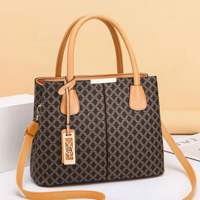 Patterned handbag with tan handles and strap on a beige background