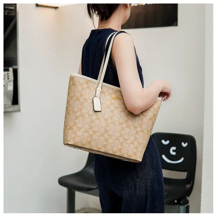 Person holding a beige handbag with a visible brand logo in an indoor setting.