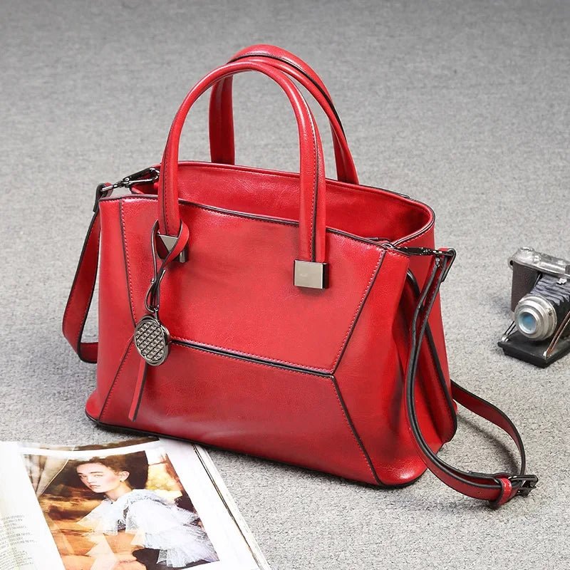 Red handbag on a gray surface with a camera and magazine