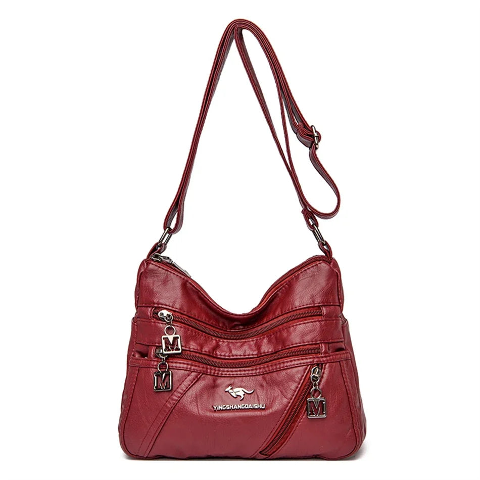 Stylish red leather handbag with a modern design, featuring secure zipper closures and a spacious interior for women.