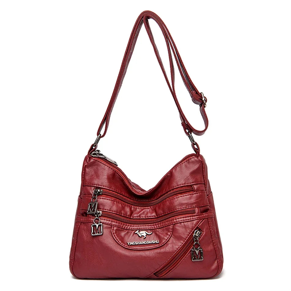 Stylish red leather handbag with a modern design, featuring secure zipper closures and a spacious interior for women.