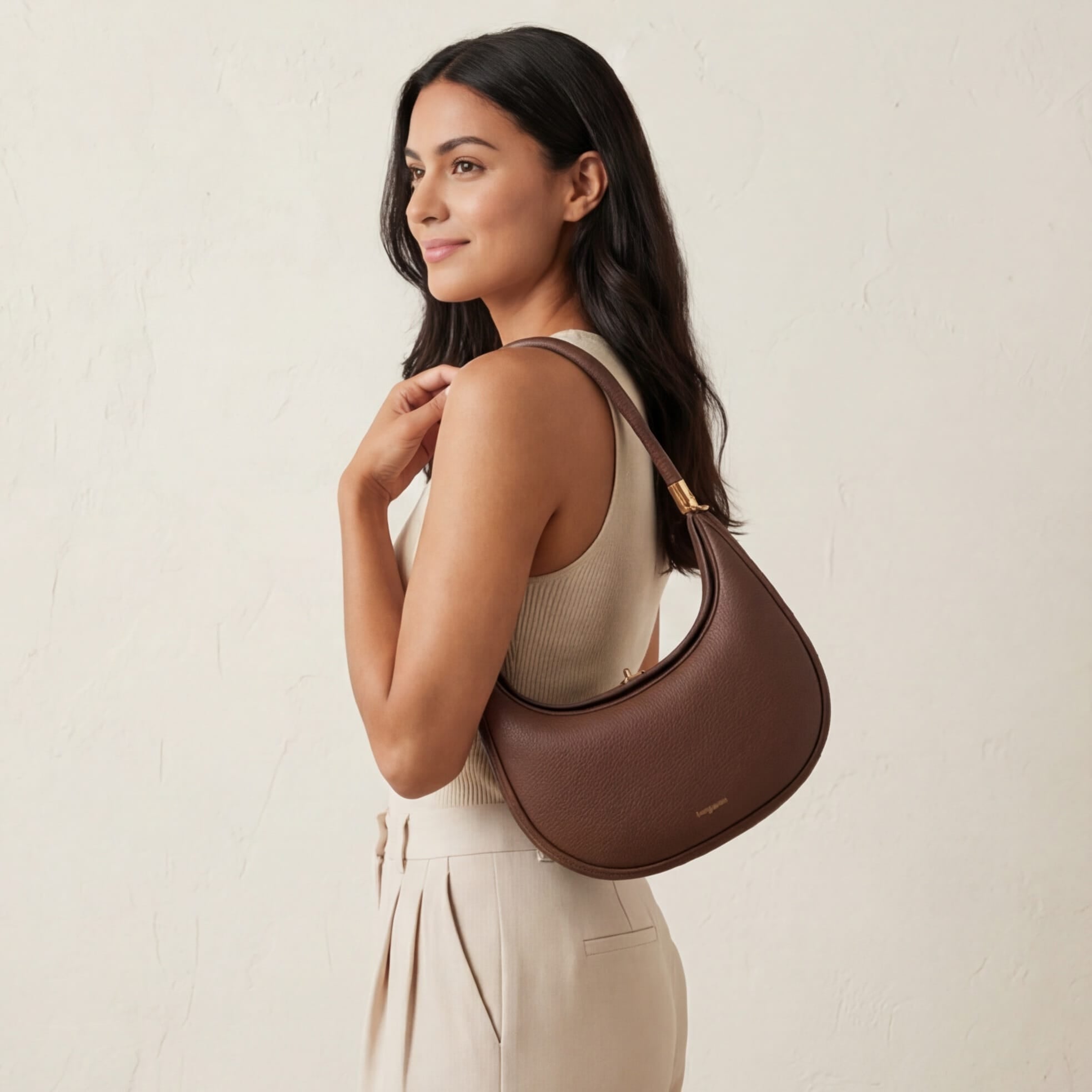Woman holding a brown handbag against a beige background