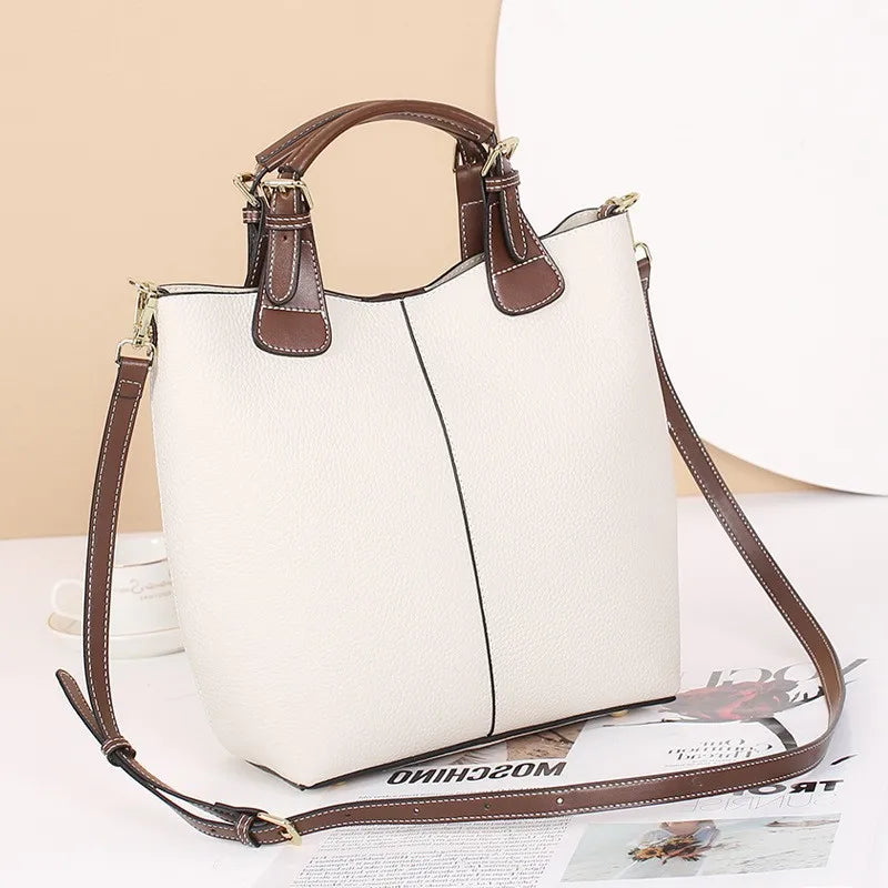 White handbag with brown handles and strap on a light background