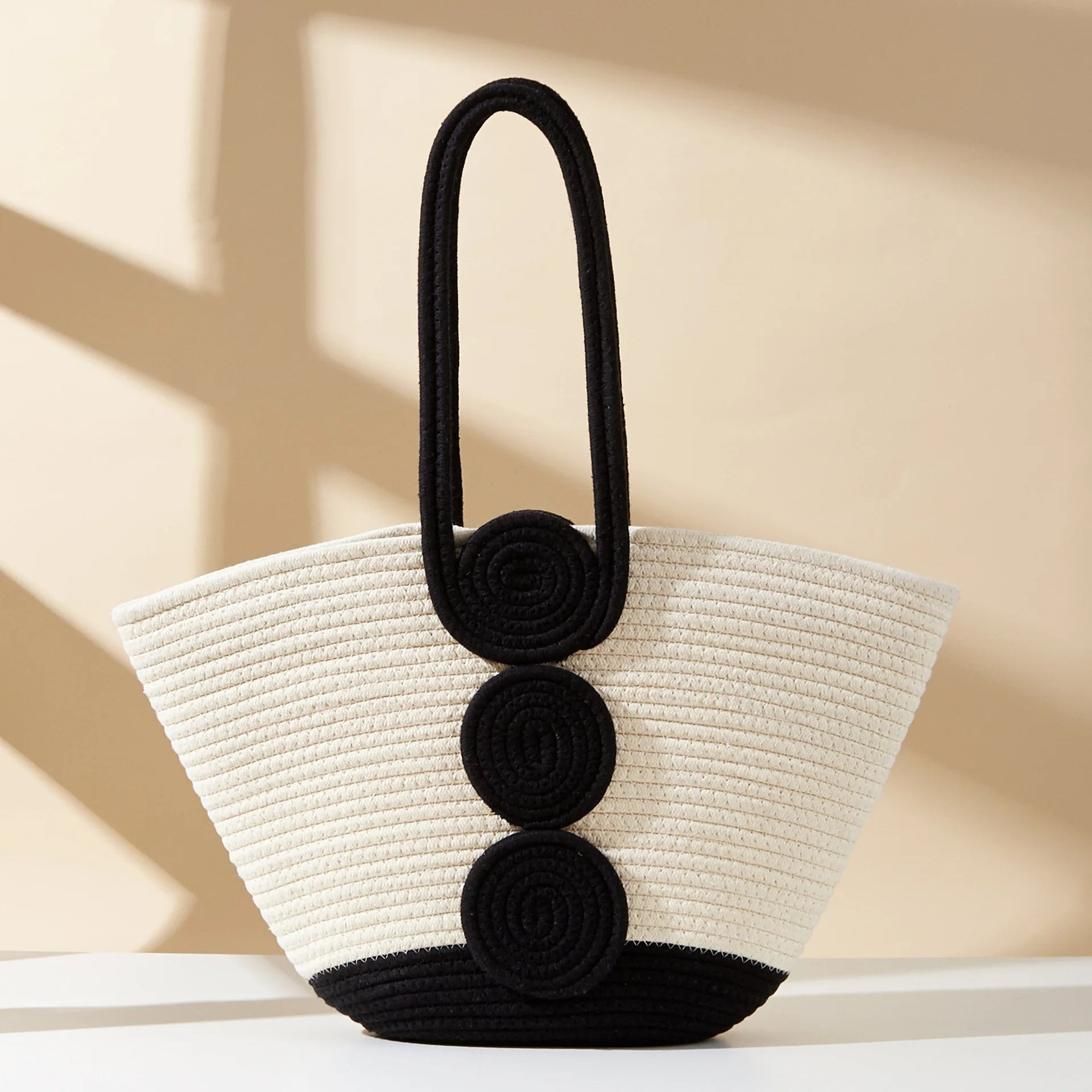 White straw handbag with black accents on a beige background