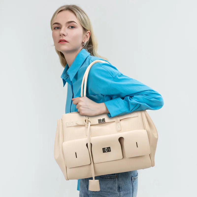 Woman holding a beige handbag against a plain background