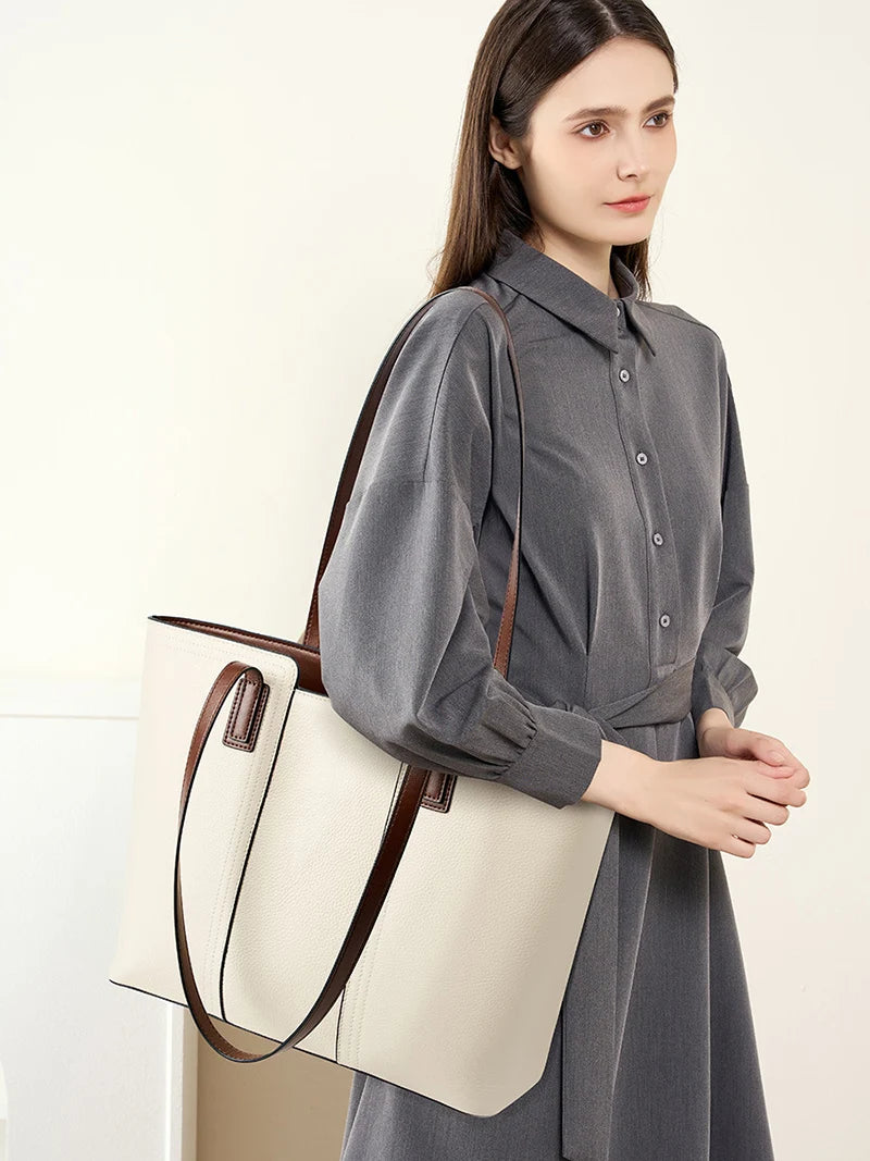 Woman holding a beige tote bag with brown straps against a white background