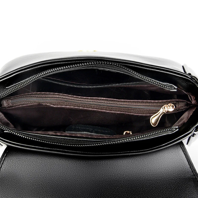 Black luxury leather handbag interior view, showcasing multiple compartments, a zippered pocket, and gold-tone zipper details.