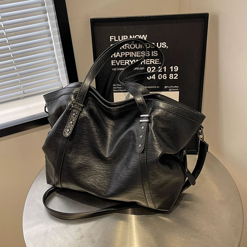 Black leather handbag on a metallic surface with a blurred background