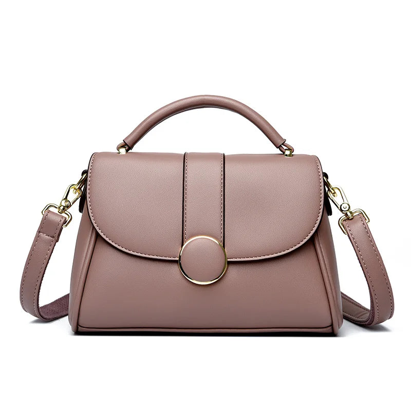 Pink luxury leather handbag with a structured shape, gold-tone circular clasp, and detachable shoulder strap, set against a white background.