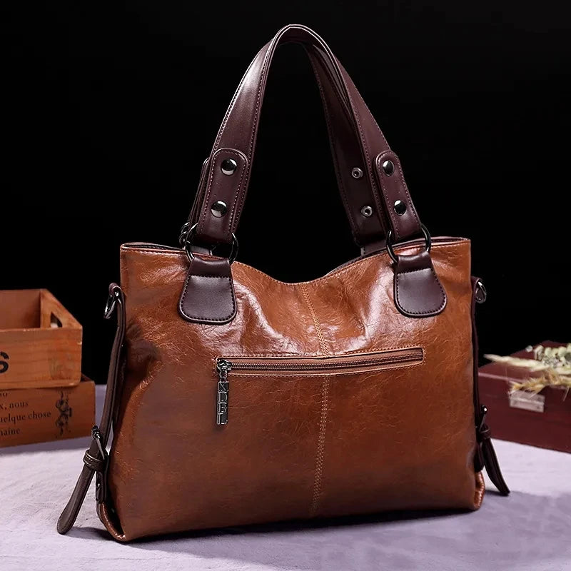 Back view of a vintage brown leather tote bag with dark brown handles, featuring a zippered pocket for added convenience.