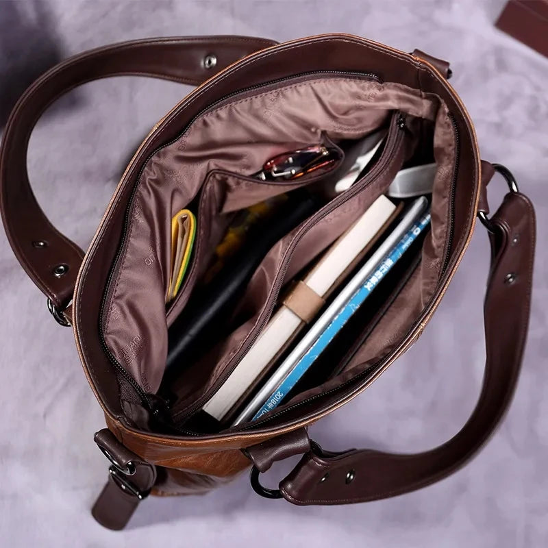 Interior view of a vintage brown leather tote bag, showcasing multiple compartments filled with books, glasses, and daily essentials