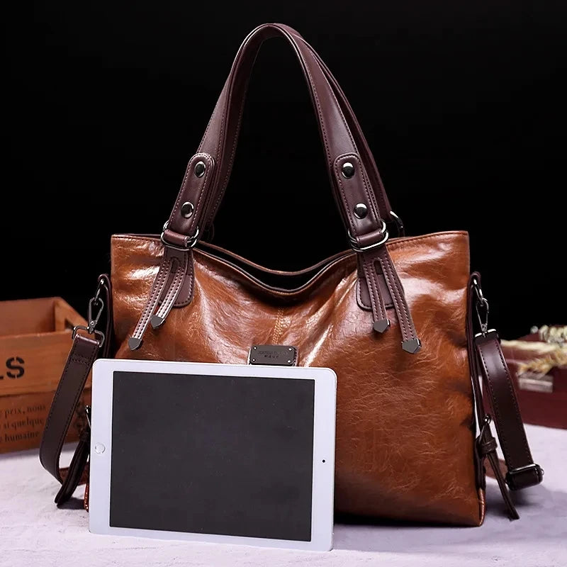 Vintage brown leather tote bag with dark brown handles, displayed with a tablet for size comparison against a black background.