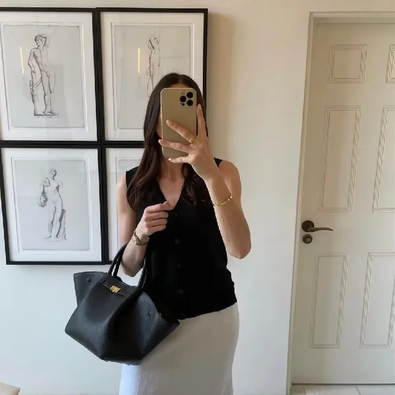 Woman taking a mirror selfie holding a black suede tote bag