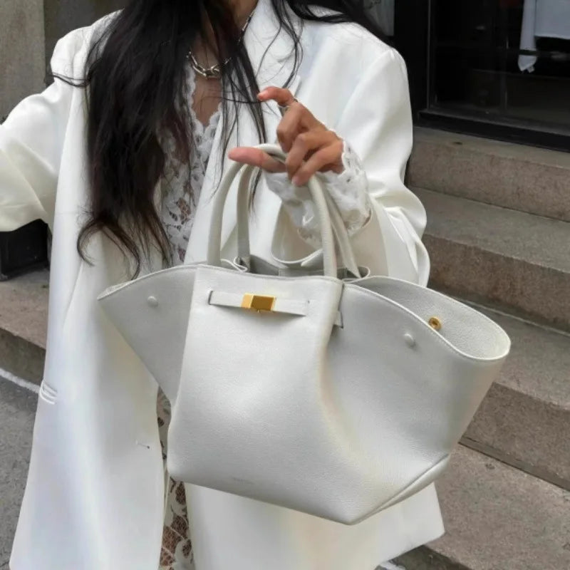 Woman in a white outfit holding a white suede tote bag