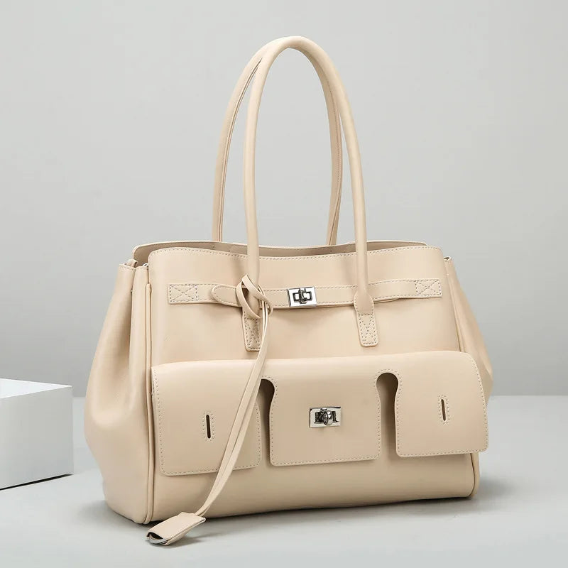 A beige luxury genuine leather tote bag with a spacious design, featuring dual handles and a secure lock closure.