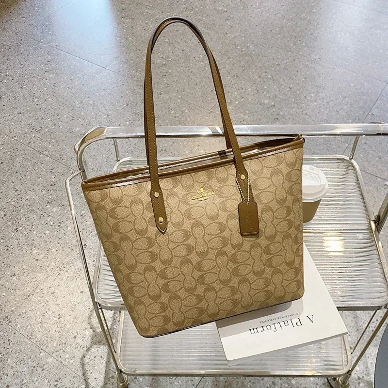 Beige handbag with brown handles on a clear glass table