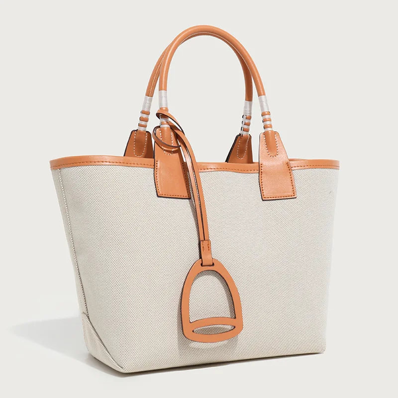 Beige tote bag with brown leather accents on a light gray background
