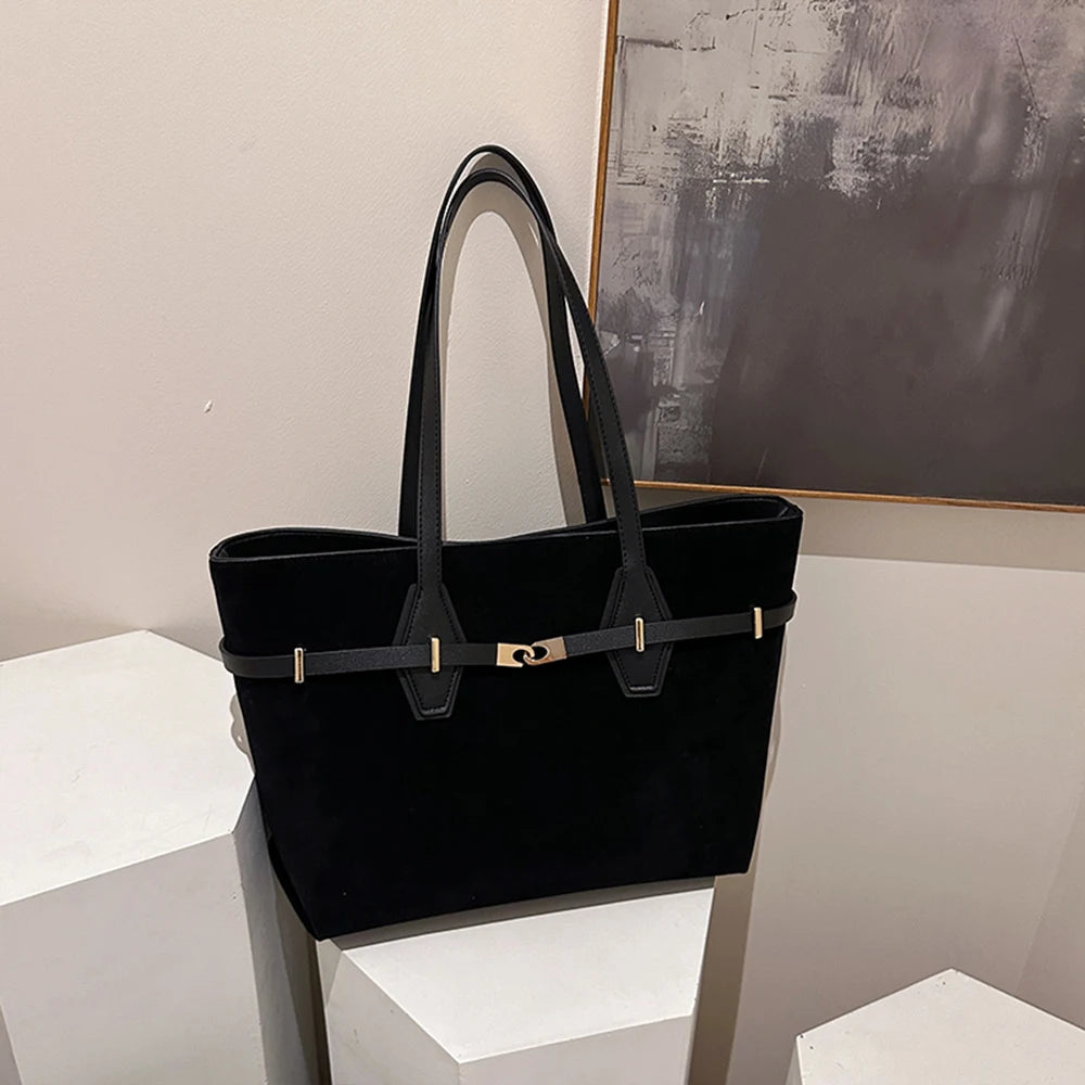 Black handbag on a white surface with a neutral background
