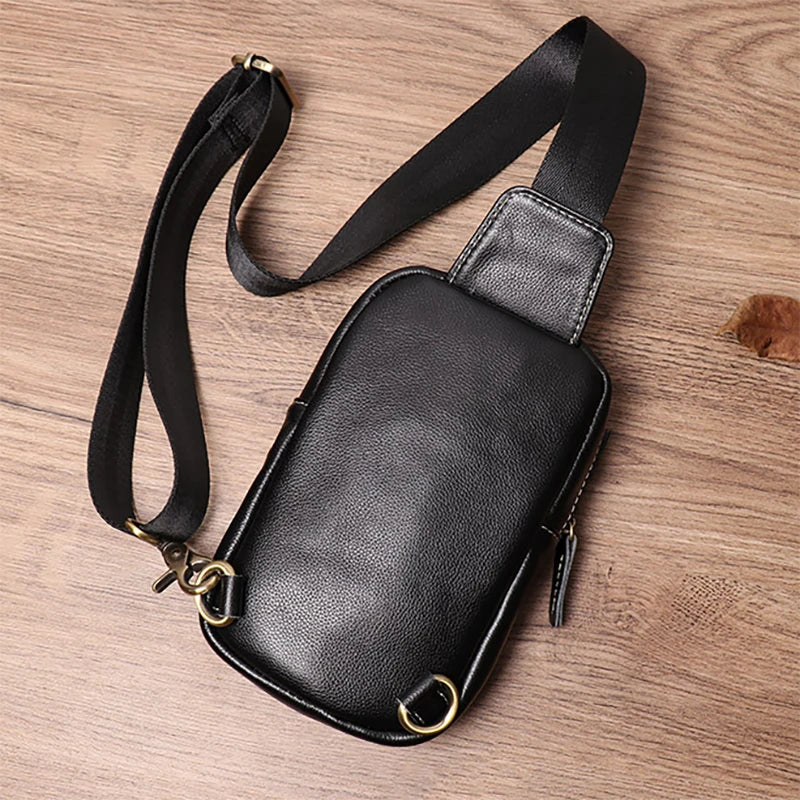 Black leather crossbody bag on a wooden surface