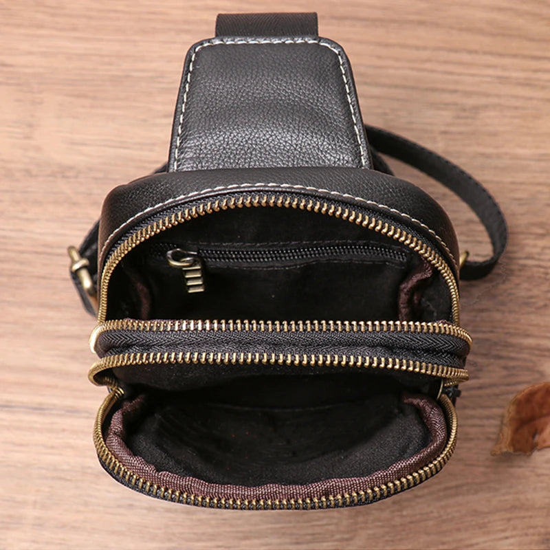 Black leather crossbody bag with gold zipper on a wooden surface