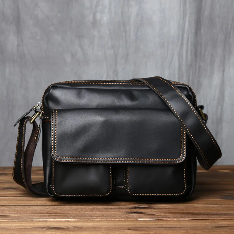 Black leather shoulder bag on a wooden surface with a gray background