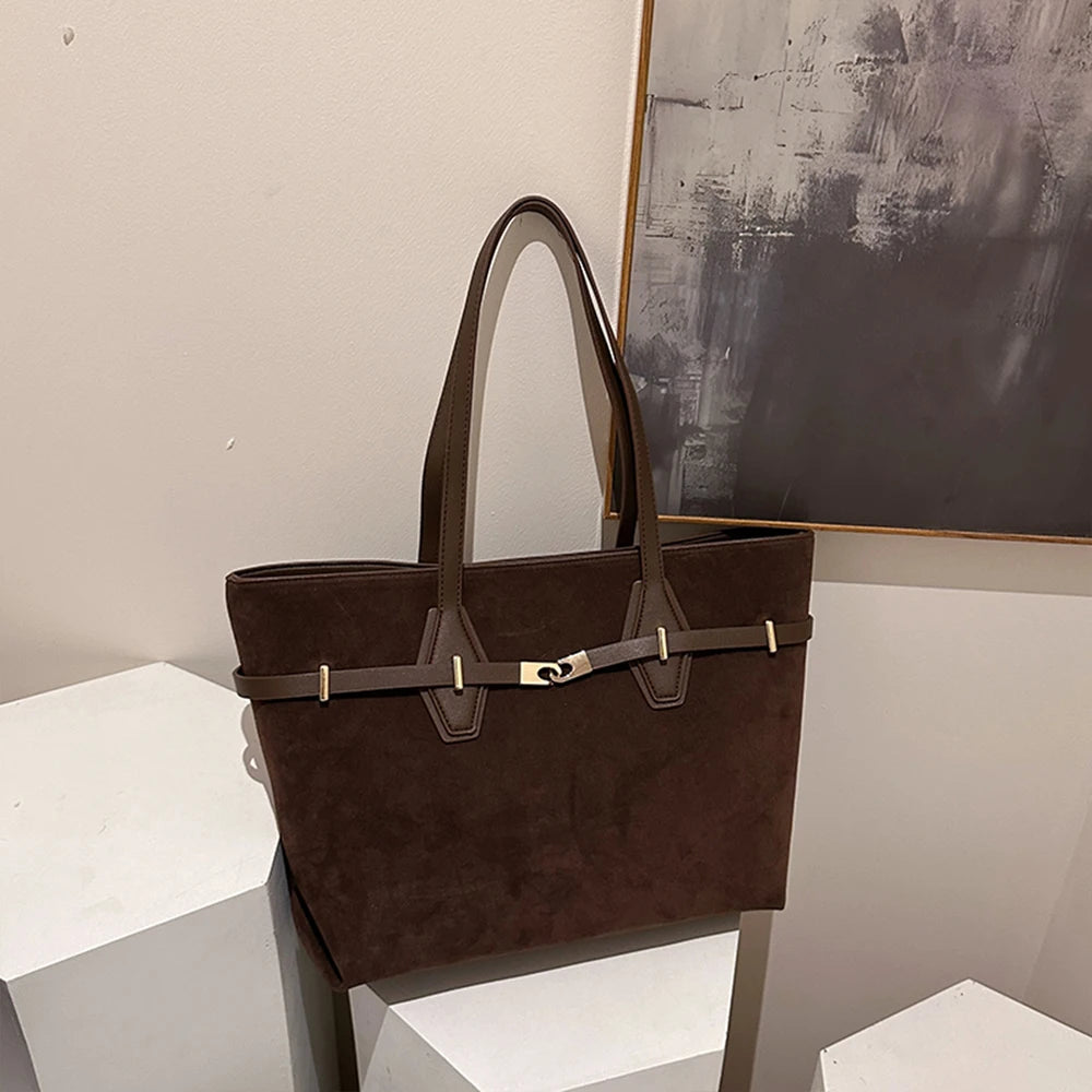 Brown handbag on a white surface with a neutral background