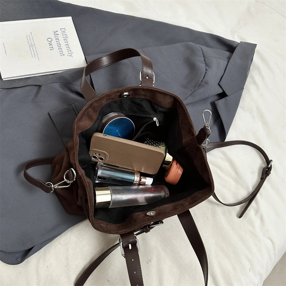 Brown leather backpack with personal items on a gray surface