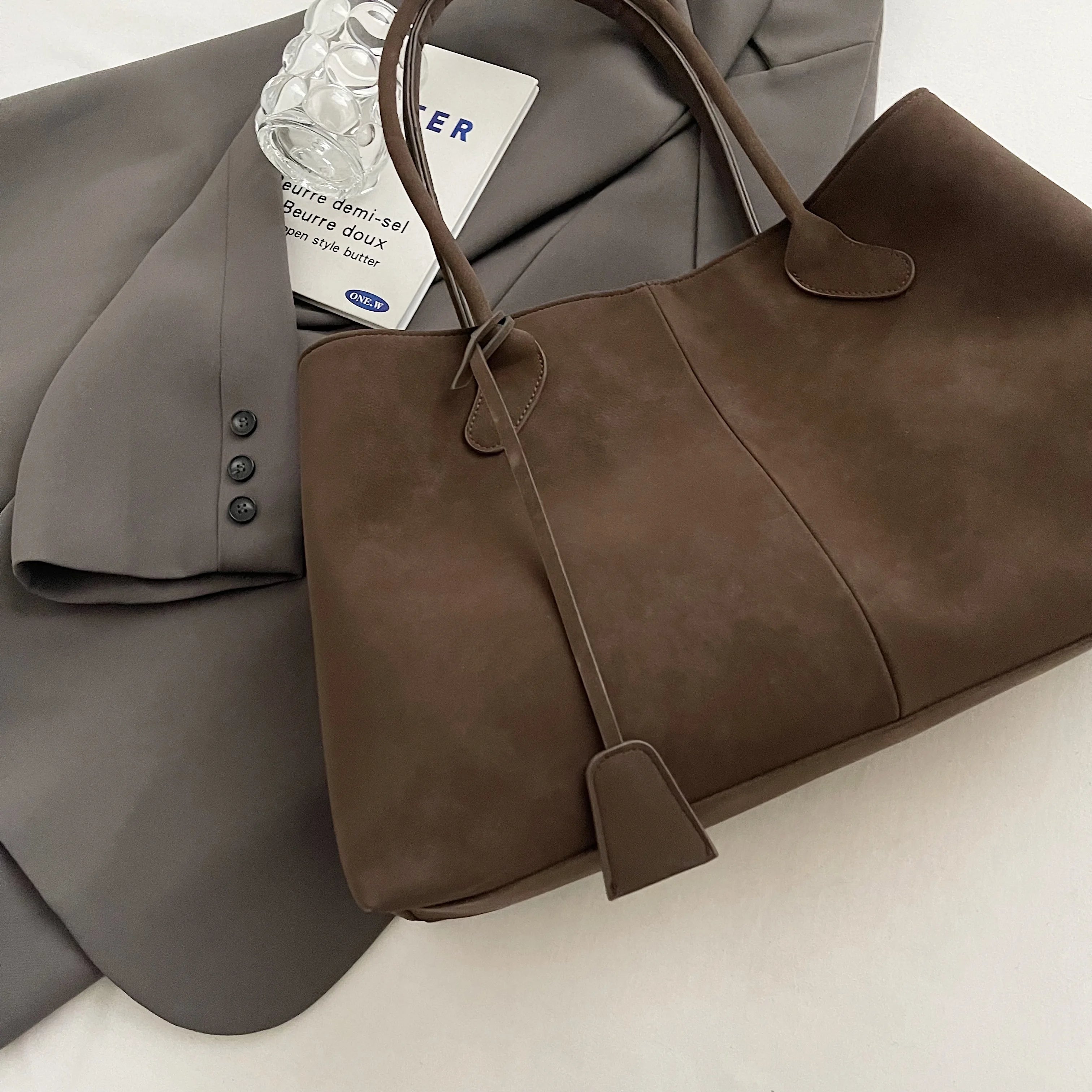 Brown leather bag on a gray suit with a visible brand tag.