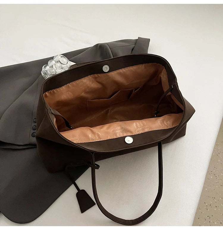 Brown leather bag with a brown interior on a light gray surface