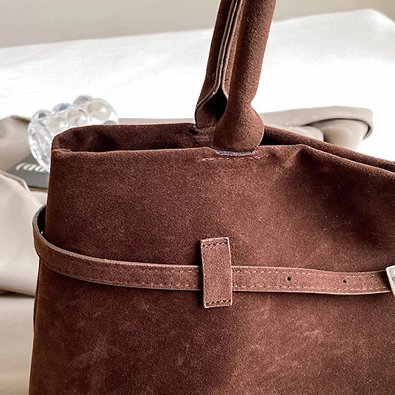 Brown leather bag with a strap on a blurred background