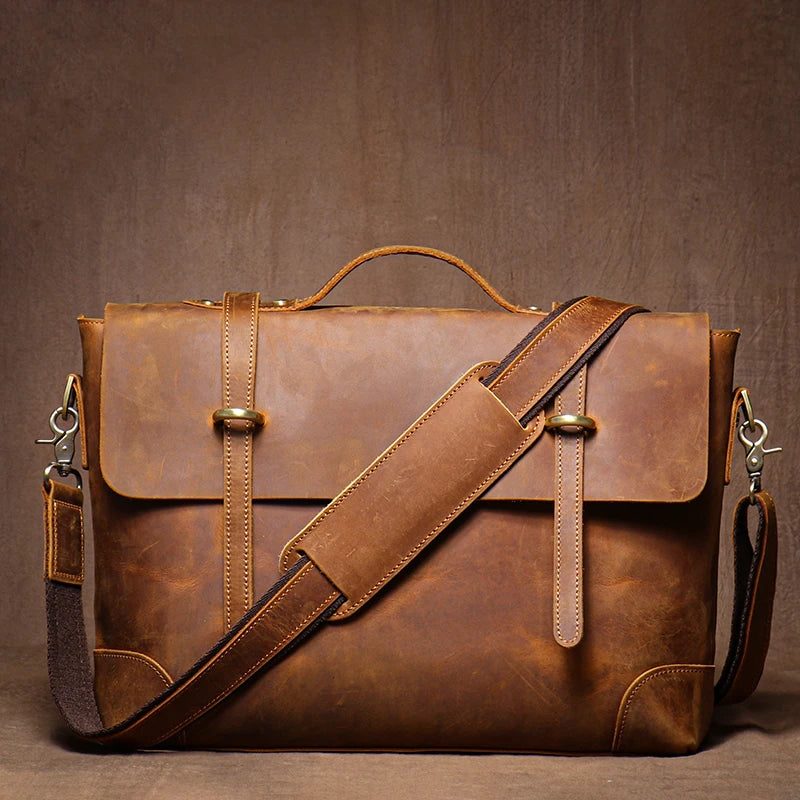 Brown leather briefcase with shoulder strap on a brown background