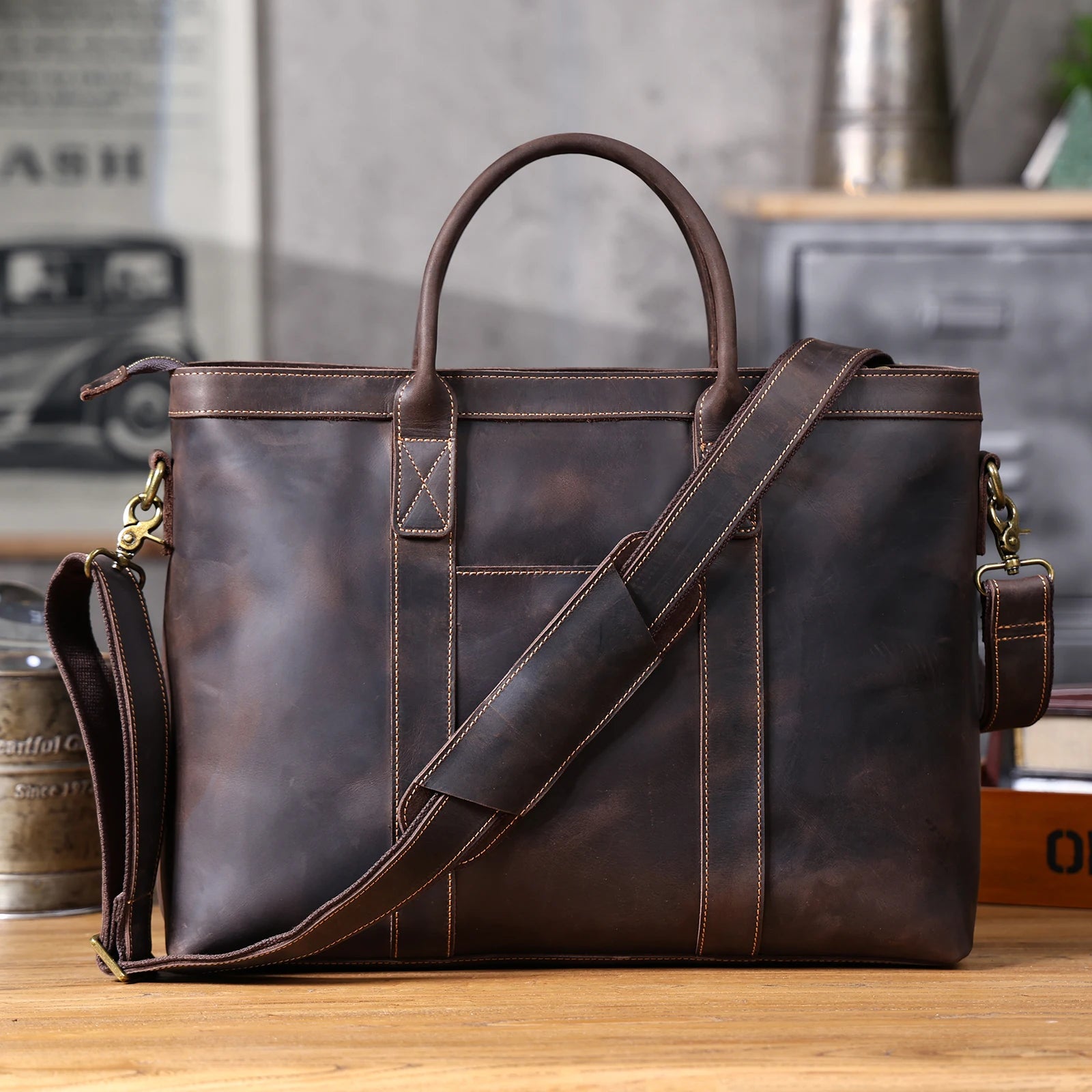 Brown leather briefcase with shoulder strap on a wooden surface