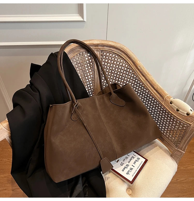 Brown leather handbag on a chair with a visible brand tag
